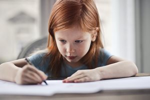 young girl writing on paper at a table
