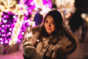 young woman in coat holding a sparkler in the winter