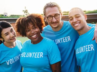 four people wearing blue volunteer shirts being cheerful