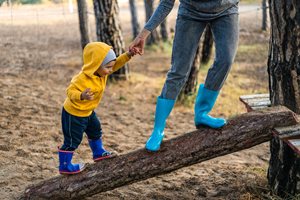 kid walking up a fallen log with a parent helping