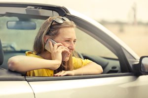 young woman in convertible car talking on a smart phone