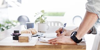 man writing with a pen at a desk