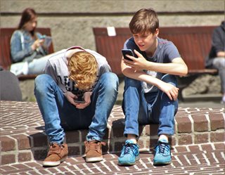 two teen boys looking at smartphones