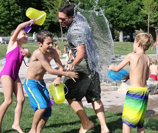 kids and a dad splashing water on each other
