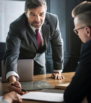 older man in suit explaining something to another person