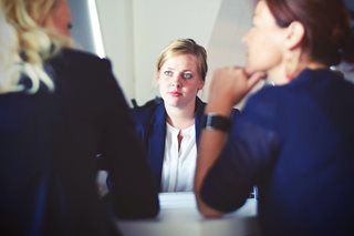 three woman dressed professionally and talking