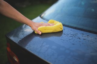person washing a car with a sponge