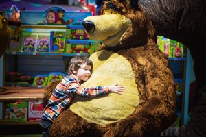 young boy hugging a massive size teddy bear