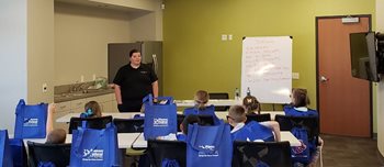 woman teaching a class of kids about saving money