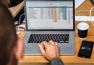 man looking at his laptop with a spreadsheet open
