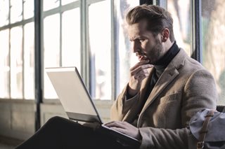 man is confused while looking at a laptop