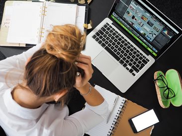 woman over a laptop holding her head confused