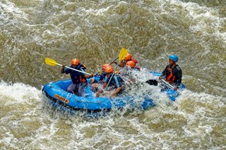 group of people paddling a boat in rapids