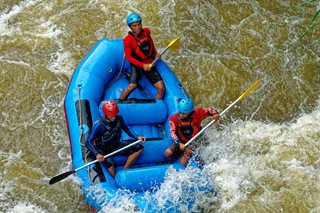 three people river rafting