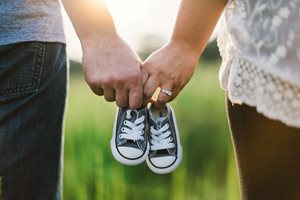 a husband and wife holding a pair of baby sneakers