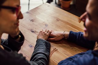 man and woman holding hands and talking at a table