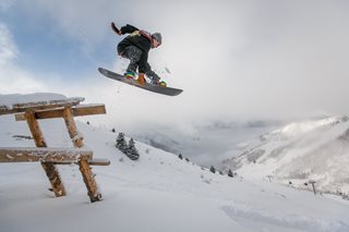 man in black jumping with a snowboard