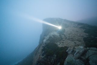 person with flashlight on a foggy mountain