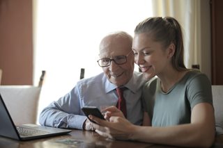 young woman and old man looking at a phone