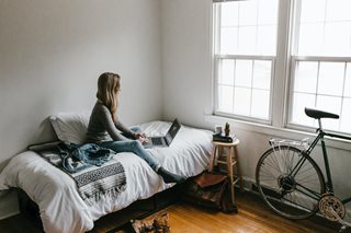woman sitting on a bed in a small apartment