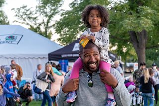 man with his daughter sitting on his shoulders at a festival
