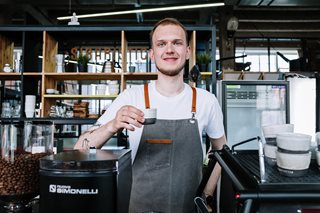 man working in coffee shop holding a cup of coffee