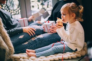 little girl eating a cupcake with presents