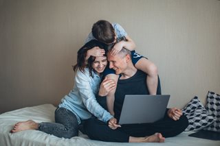 man, woman and child playing and looking at laptop