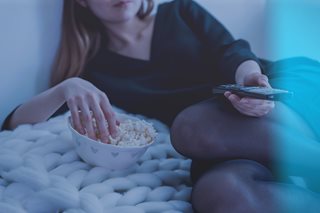 woman watching TV and eating popcorn