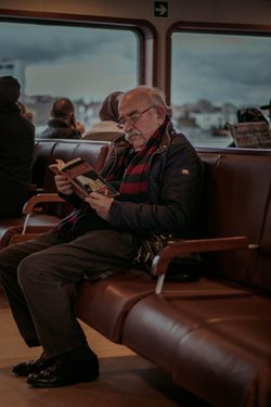 old man sitting in an airport reading a book