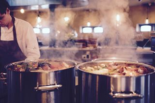 woman chef cooking two pots of soup