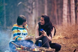 two women chatting next to a campfire