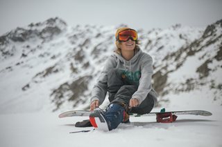 man in mountains sitting on snowboard
