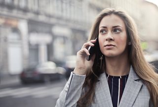 woman talking on a phone and wearing a gray suit