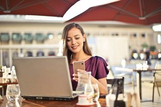 woman sitting outside with a smartphone and laptop