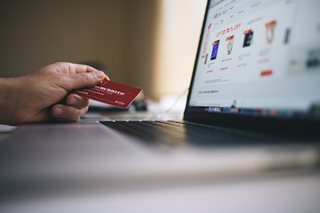 hand holding a credit card looking at a laptop