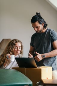 young couple looking at a laptop in an empty home