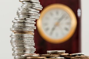 stock of coins with blurry clock in the background