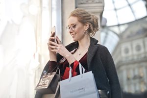 young woman carrying shopping bags and looking at her smart phone