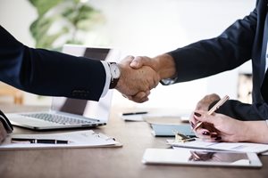 two businessmen shaking hands over a table
