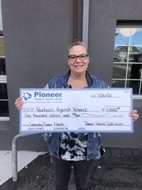 woman in glasses holding large check
