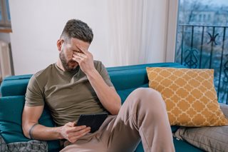 man frustrated looking at tablet