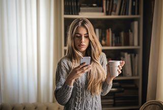 Woman on phone with a mug of coffee