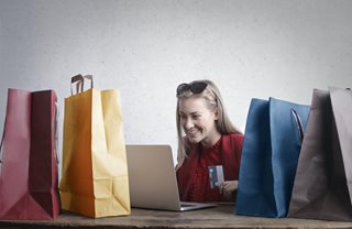 woman online shopping with gift bags all around her