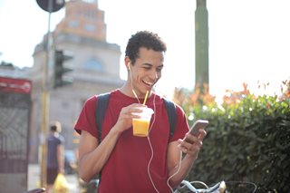 young man with a drink looking at phone