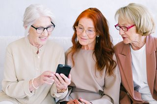 three older woman all looking at a phone