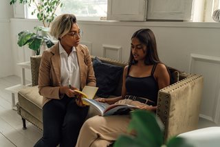 two black women talking on a couch