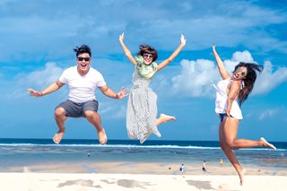 three people jumping on a beach