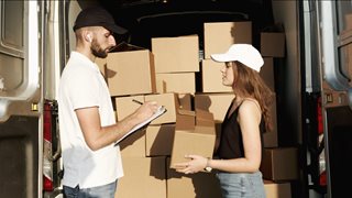 man signing for something while woman holds a box