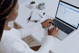 black woman on laptop looking at facebook